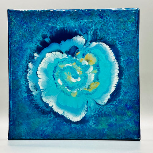 An iridescent metallic painting with blue spiral flower with accents of pearl white and gold. Painted on an 8 inch by 8 inch gallery wrapped cotton canvas that is 1.5 inch thick. Finished with resin to make it look like it's under glass.